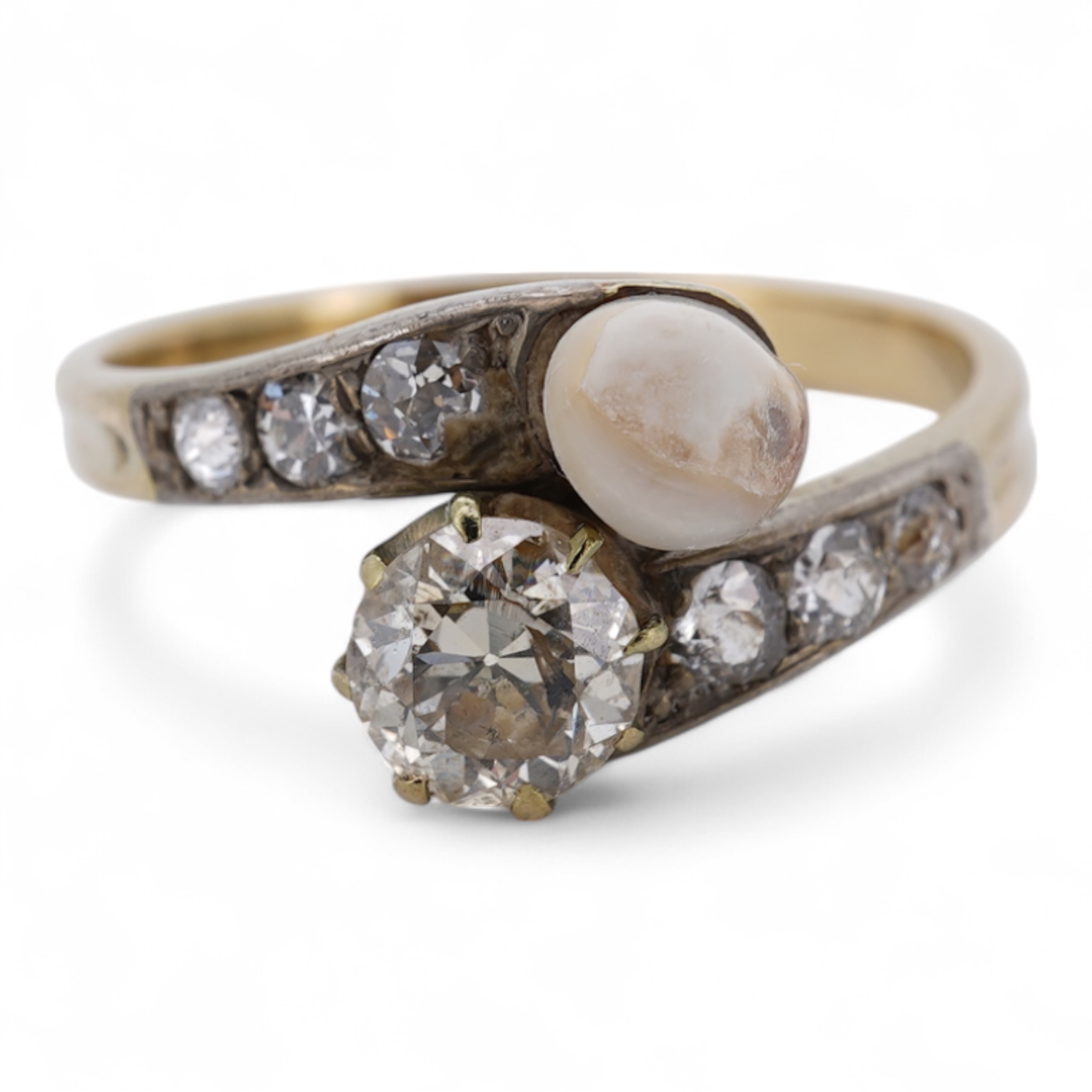 A yellow meta (stamped 18ct) cultured pearl and diamond set crossover ring, with six stone graduated diamond set shoulders, size M, gross weight 2.6 grams (pearl nacre a.f.).